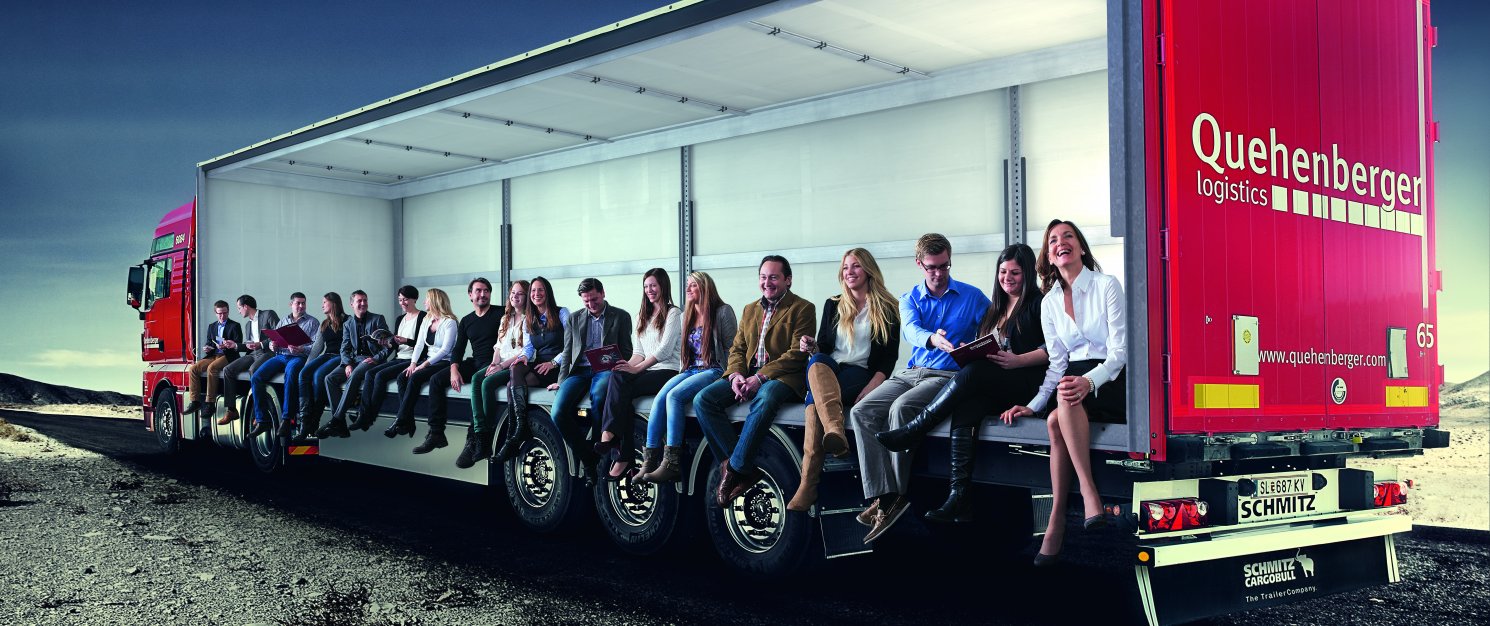 Екипът на Квеенбергер Лоджистикс стои в товарно помещение на камион.
